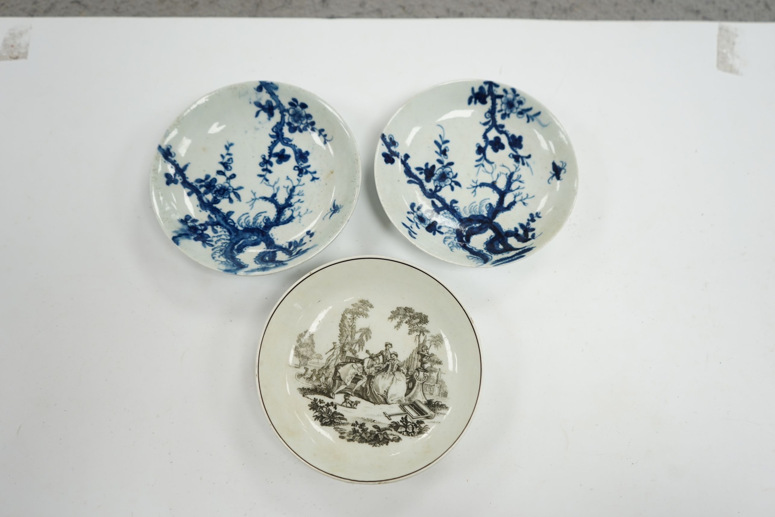 An 18th century Worcester saucer printed by Hancock and a pair of 18th century Liverpool prunus root saucers, Hancock saucer 12cm diameter. Condition - fair to good